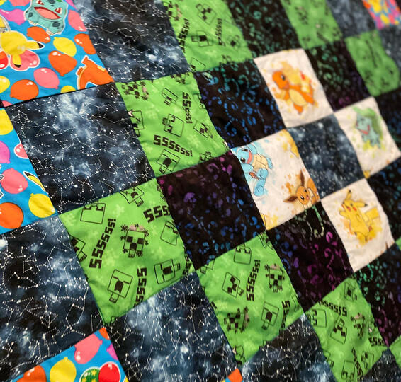 A basic quilt made of squares with galaxy, creepers (minecraft), and pokemon designed fabric.